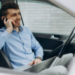 Man working on laptop inside of his car